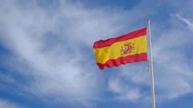 İspanyol bayrağı zarif bir şekilde mavi gökyüzüne doğru dalgalanıyor. Spains kültürel kimliğinin özünü yakalayan ulusal gurur, birlik ve mirasın güçlü bir sembolü.