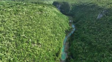 Korana nehri Plitvice yakınlarındaki yeşil tepelerden akar. Korana Nehri 'nin tepeler ve ormanlar boyunca kıvrımlı manzarası. Sıcak güneş ışığı ve Hırvat kırsalının zengin dokularına sahip taze bahar manzarası