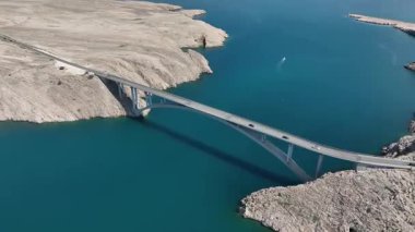 Mavi Adriyatik Denizi 'nin karşısındaki Köprü Pag Adası. Hırvatistan 'ı Pag Adası' na bağlayan köprü geniş çaplı insansız hava aracı görüntüsü. Çarpıcı deniz, kayalık kıyı şeridi, ılık bahar ışığı tonları dramatik bir kompozisyon oluşturur..