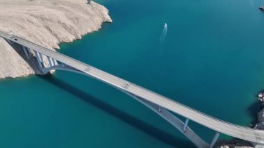 Mavi Adriyatik Denizi 'nin karşısındaki Köprü Pag Adası. Hırvatistan 'ı Pag Adası' na bağlayan köprü geniş çaplı insansız hava aracı görüntüsü. Çarpıcı deniz, kayalık kıyı şeridi, ılık bahar ışığı tonları dramatik bir kompozisyon oluşturur..