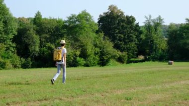 Kırsal alanlarda yürüyüş yapan bir kadın, açık araziler, temiz hava ve huzurlu kırsal manzarayla çevrili. Açık havanın doğal güzelliğini ve sükunetini seviyor..