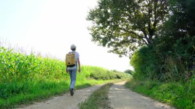 Kırsal alanlarda yürüyüş yapan bir kadın, açık araziler, temiz hava ve huzurlu kırsal manzarayla çevrili. Açık havanın doğal güzelliğini ve sükunetini seviyor..
