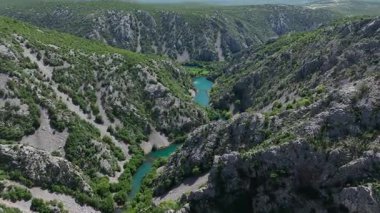 Krnjeza ve Krupa nehirlerinin birleştiği hava manzarası. Dolambaçlı Zrmanja nehrinin havadan çekimleri derin kanyonu, bereketli bahar renklerini ve uzak yolları kesiyor.