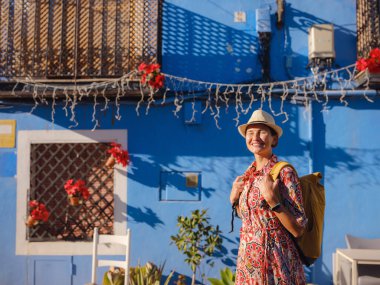Kıyı kasabası La Vila Joiosa ya da Villajoyosa 'nın renkli caddelerinde gezen kadın. Güney İspanya 'da Villajoyosa' nın deniz kenarındaki villasında renkli evler