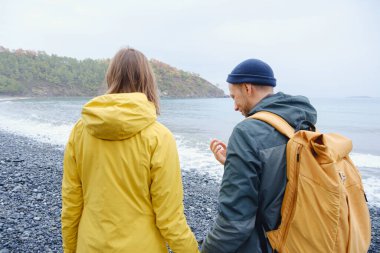 Çiftler Türk kıyı şeridini seviyor. Taşlarda oturmak, deniz dalgalarını izlemek, birlikte dinlenmek, sakin mavi suyun yanında, yumuşak kış ışığı altında romantik bir an..