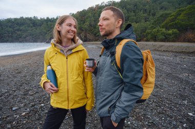 Çiftler Türk kıyı şeridini seviyor. Taşlarda oturmak, deniz dalgalarını izlemek, birlikte dinlenmek, sakin mavi suyun yanında, yumuşak kış ışığı altında romantik bir an..