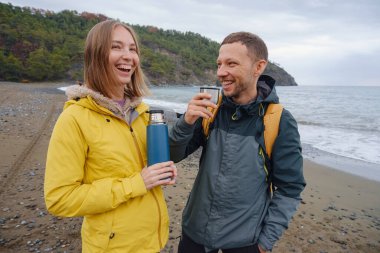 Çiftler Türk kıyı şeridini seviyor. Taşlarda oturmak, deniz dalgalarını izlemek, birlikte dinlenmek, sakin mavi suyun yanında, yumuşak kış ışığı altında romantik bir an..