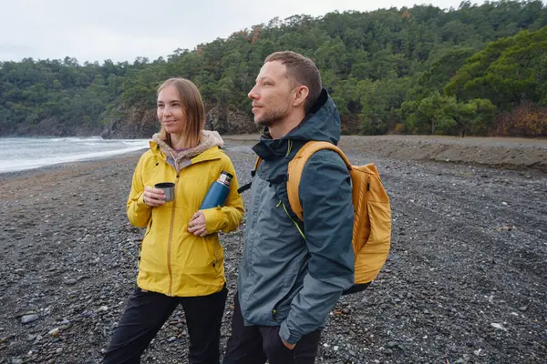 Çiftler Türk kıyı şeridini seviyor. Taşlarda oturmak, deniz dalgalarını izlemek, birlikte dinlenmek, sakin mavi suyun yanında, yumuşak kış ışığı altında romantik bir an..