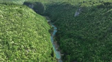 Korana nehri Plitvice yakınlarındaki yeşil tepelerden akar. Korana Nehri 'nin tepeler ve ormanlar boyunca kıvrımlı manzarası. Sıcak güneş ışığı ve Hırvat kırsalının zengin dokularına sahip taze bahar manzarası