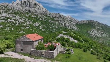 Tulove Grede dağları yakınlarındaki St. Francis kilisesinin insansız hava aracı görüntüsü. Tulove Grede Dağı 'nın yanındaki küçük taş kilise, uzak Hırvat manzarasındaki yaban tepeleri ve bahar bitkileri tarafından çerçevelenmiş yukarıdan görülüyor.