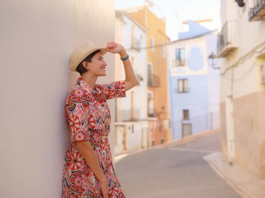 İspanyol kıyı kasabası La Vila Joiosa ya da Villajoyosa 'nın renkli caddelerinde gezen kadın. Güneşli kış atmosferi Akdeniz mimarisinin ve sakin deniz yaşamının cazibesini vurguluyor