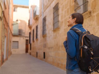 İspanya 'nın Alicante eyaletinin büyüleyici dar sokaklarında gezinen, tarihi Akdeniz mimarisi ile çevrili, barışçıl atmosfer ve kültürel ortamın tadını çıkaran genç bir kadın..