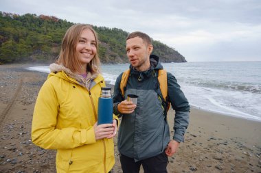 Çiftler Türk kıyı şeridini seviyor. Taşlarda oturmak, deniz dalgalarını izlemek, birlikte dinlenmek, sakin mavi suyun yanında, yumuşak kış ışığı altında romantik bir an..