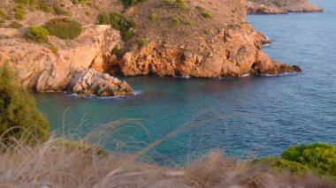 Cala Tio Ximo kıyı şeridi Aralık akşamında ele geçirildi. Sakin kış denizi, yumuşak gün batımı parıltısı, Benidorm yakınlarındaki küçük adanın huzurlu manzarası. Sessiz doğal güzellik, insan yok, sadece deniz ve gökyüzü..