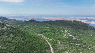 İlkbaharda Velebit dağ sırasından geçen manzara, bahar güneşinde yeşil Velebit dağlarından geçen yol, Hırvatların doğal manzarasını ve huzurlu uzak arazisini gösteriyor