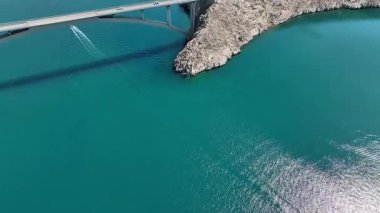 Mavi Adriyatik Denizi 'nin karşısındaki Köprü Pag Adası. Hırvatistan 'ı Pag Adası' na bağlayan köprü geniş çaplı insansız hava aracı görüntüsü. Çarpıcı deniz, kayalık kıyı şeridi, ılık bahar ışığı tonları dramatik bir kompozisyon oluşturur..