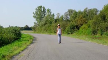 Kırsal alanlarda yürüyüş yapan bir kadın, açık araziler, temiz hava ve huzurlu kırsal manzarayla çevrili. Açık havanın doğal güzelliğini ve sükunetini seviyor..