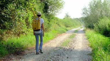Kırsal alanlarda yürüyüş yapan bir kadın, açık araziler, temiz hava ve huzurlu kırsal manzarayla çevrili. Açık havanın doğal güzelliğini ve sükunetini seviyor..