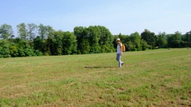 Kırsal alanlarda yürüyüş yapan bir kadın, açık araziler, temiz hava ve huzurlu kırsal manzarayla çevrili. Açık havanın doğal güzelliğini ve sükunetini seviyor..