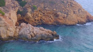 Cala Tio Ximo kıyı şeridi Aralık akşamında ele geçirildi. Sakin kış denizi, yumuşak gün batımı parıltısı, Benidorm yakınlarındaki küçük adanın huzurlu manzarası. Sessiz doğal güzellik, insan yok, sadece deniz ve gökyüzü..