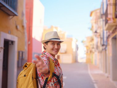 İspanyol kıyı kasabası La Vila Joiosa ya da Villajoyosa 'nın renkli caddelerinde gezen kadın. Güneşli kış atmosferi Akdeniz mimarisinin ve sakin deniz yaşamının cazibesini vurguluyor