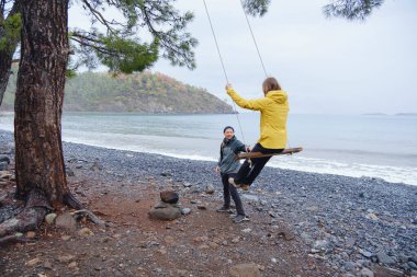 Çiftler Türk kıyı şeridini seviyor. Taşlarda oturmak, deniz dalgalarını izlemek, birlikte dinlenmek, sakin mavi suyun yanında, yumuşak kış ışığı altında romantik bir an..