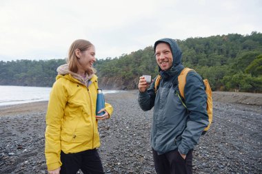 Çiftler Türk kıyı şeridini seviyor. Taşlarda oturmak, deniz dalgalarını izlemek, birlikte dinlenmek, sakin mavi suyun yanında, yumuşak kış ışığı altında romantik bir an..