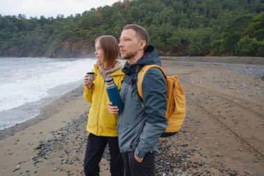 Çiftler Türk kıyı şeridini seviyor. Taşlarda oturmak, deniz dalgalarını izlemek, birlikte dinlenmek, sakin mavi suyun yanında, yumuşak kış ışığı altında romantik bir an..