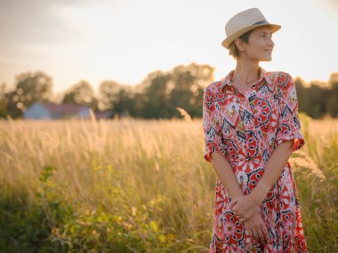 Yaz sonlarında Avrupa 'nın pitoresk alanlarında yürüyen genç bir kadın. Altın güneş ışığı, yemyeşil yemyeşil ve sakin kırsal atmosfer huzurlu bir kırsal alan yaratır..