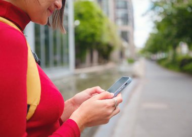 Frankfurt 'taki turist kadın akıllı telefon kullanıyor, daktilo kullanıyor ya da yön arıyor, modern kentsel çevre ile çevrili, hareketli şehirde beklerken teknolojiyle meşgul oluyor..