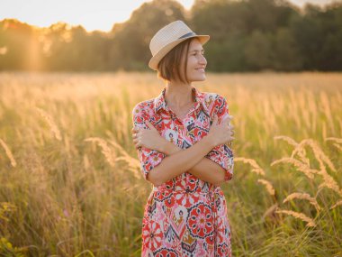 Kendini kucaklayan genç bir kadın, hareket halindeki bir aşk, akıl sağlığı savunucusu, iç huzuru bulmak için Avrupa 'nın kırsal kesimlerinde kendi kendine bakım uygulayan.