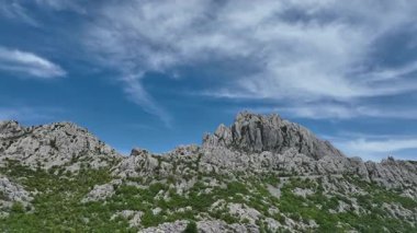 Tulove Grede kayalık tepeleri ilkbahar güneşinde tepeden. İnsansız hava aracı Hırvatistan 'daki Tulove Grede' in engebeli kireçtaşı zirvelerinde uçarak dramatik uçurumları ve panoramik manzaralı vahşi bahar doğasını gözler önüne seriyor.
