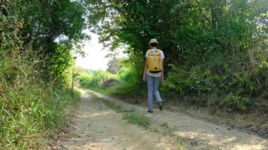 Kırsal alanlarda yürüyüş yapan bir kadın, açık araziler, temiz hava ve huzurlu kırsal manzarayla çevrili. Açık havanın doğal güzelliğini ve sükunetini seviyor..