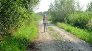 Kırsal alanlarda yürüyüş yapan bir kadın, açık araziler, temiz hava ve huzurlu kırsal manzarayla çevrili. Açık havanın doğal güzelliğini ve sükunetini seviyor..