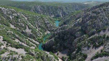 Krnjeza ve Krupa nehirlerinin birleştiği hava manzarası. Dolambaçlı Zrmanja nehrinin havadan çekimleri derin kanyonu, bereketli bahar renklerini ve uzak yolları kesiyor.