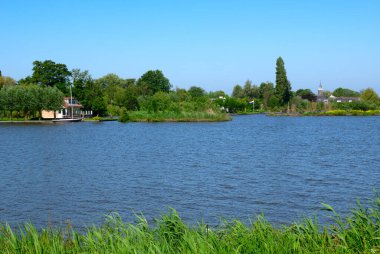 Mavi suları ve ağaçları olan bir göl manzarası