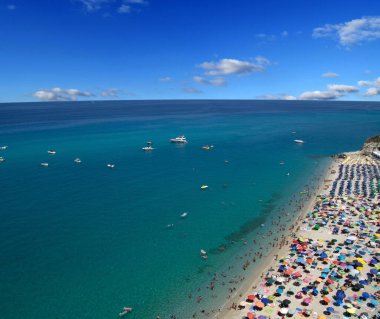 Turkuvaz suyu ve kumu olan deniz plajı insanların dinlendiği, yüzdüğü ve şemsiyelerle güneşlendiği yer.