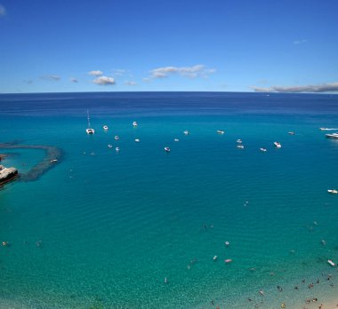 Turkuvaz suyu ve kumu olan deniz plajı insanların dinlendiği, yüzdüğü ve şemsiyelerle güneşlendiği yer.