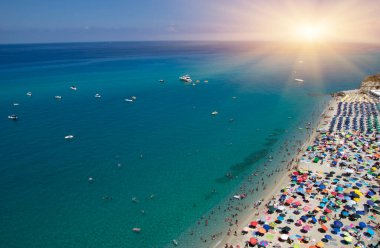 Turkuvaz suyu ve kumu olan deniz plajı insanların dinlendiği, yüzdüğü ve şemsiyelerle güneşlendiği yer.