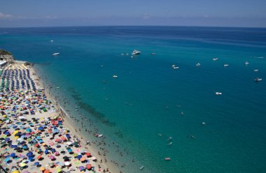 Turkuvaz suyu ve kumu olan deniz plajı insanların dinlendiği, yüzdüğü ve şemsiyelerle güneşlendiği yer.