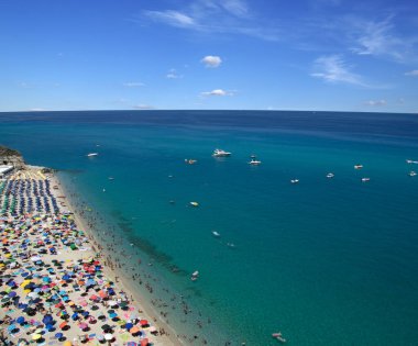 Turkuvaz suyu ve kumu olan deniz plajı insanların dinlendiği, yüzdüğü ve şemsiyelerle güneşlendiği yer.