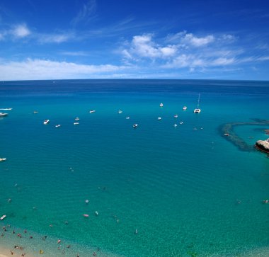 Turkuvaz suyu ve kumu olan deniz plajı insanların dinlendiği, yüzdüğü ve şemsiyelerle güneşlendiği yer.