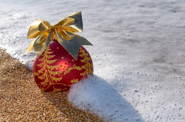 在沙滩上的圣诞树上装饰着海浪中的泡沫 图库图片