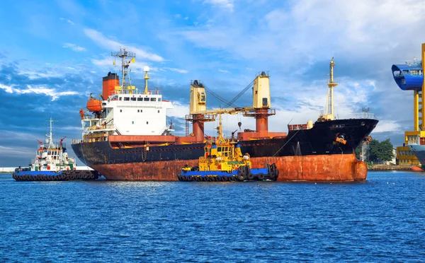 オデッサの港の水に小麦の輸送のためのバルクキャリア 2つの海のタグボートは ウクライナのオデッサ市の港で古いドライ貨物船を係留 — ストック写真