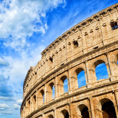 Roman Coliseum - ancient amphitheatre in the centre of the city of Rome against a blue sky on a sunny day, Italy                                