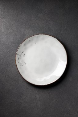 empty white plate on black table, top view