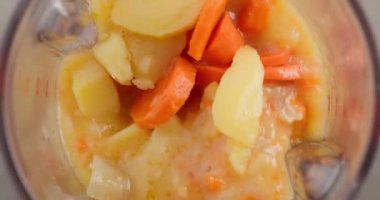 process of making vegetable cream soup. boiled carrot, potato and onion mixing in blender, top view