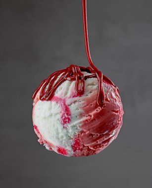 vanilla and strawberry ice cream with chocolate sauce on grey background