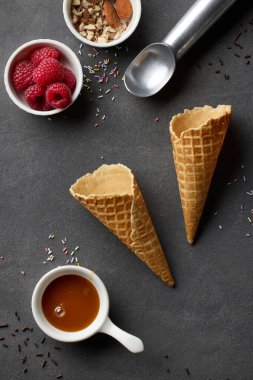 various ice cream serving ingredients on dark grey table background, top view