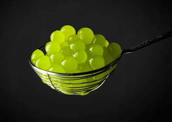green jelly balls for making bubble tea in a strainer on black background